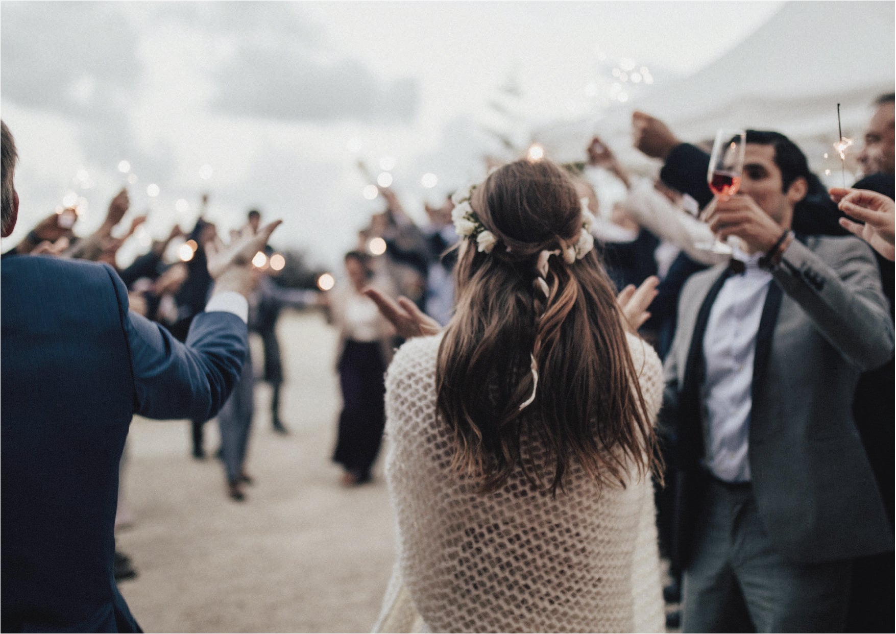 Novia llegando a su boda acompañada por los invitados con bengalas