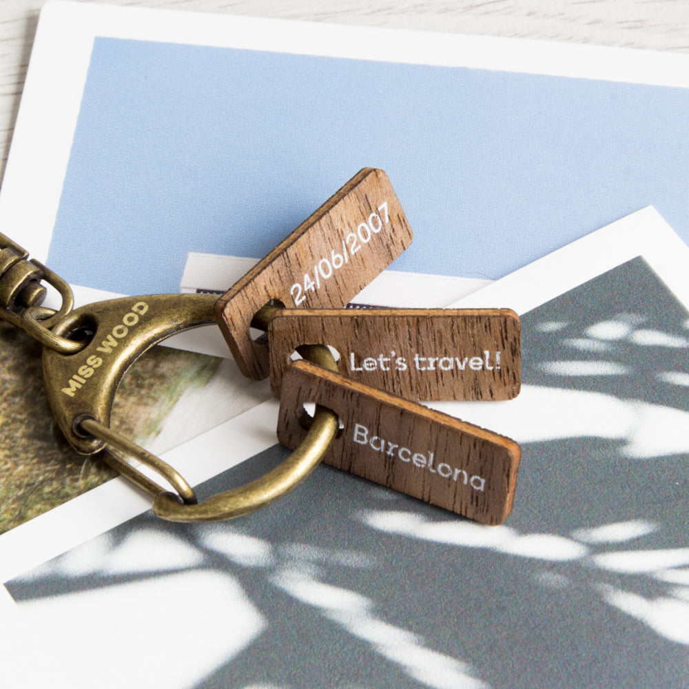 Varias tags personalizadas con texto, colgadas en un tag collector encima de unas polaroids